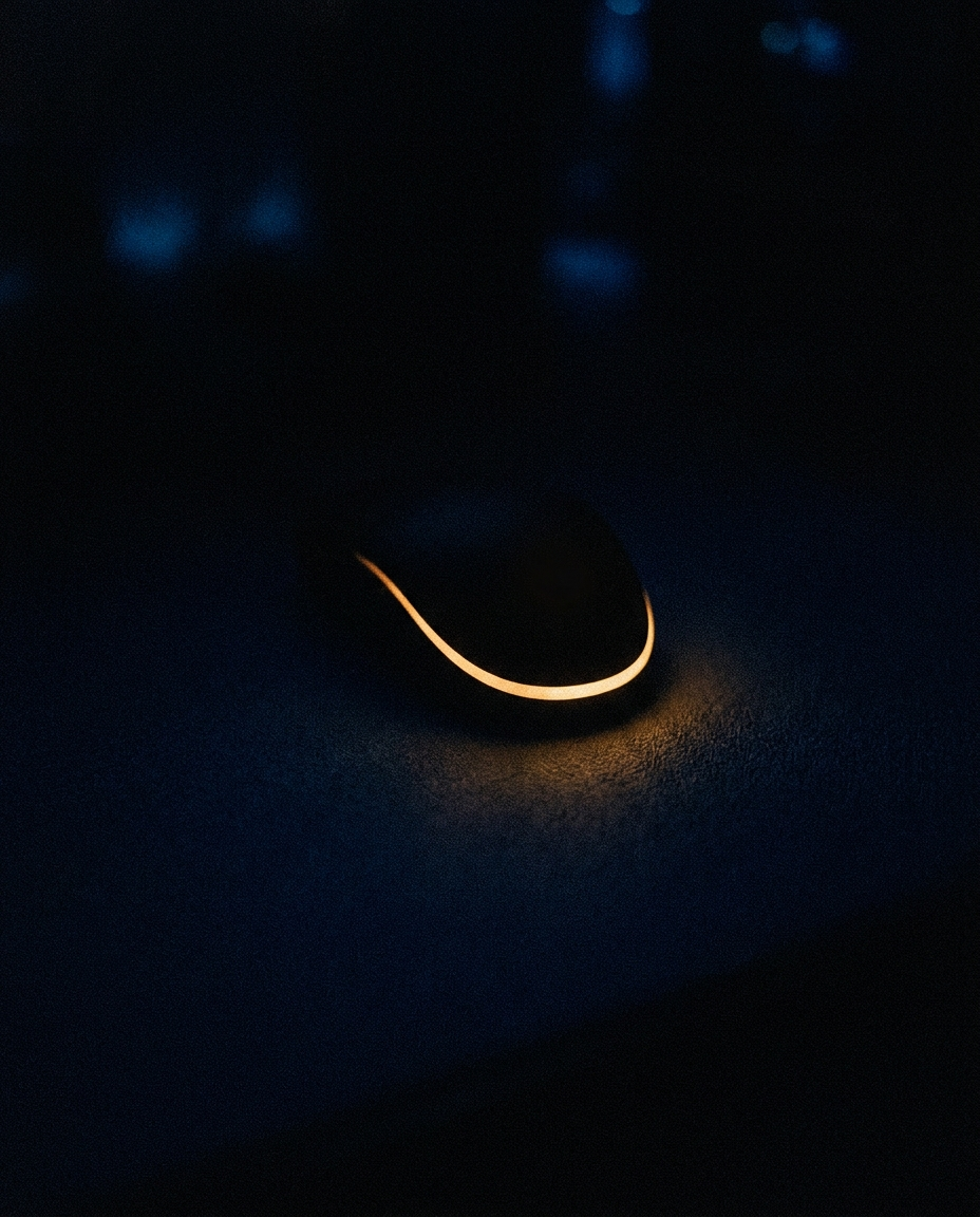 Silhouette mystérieuse d'un objet de bien-être dans l'obscurité, éclairée par un fin liseré ambré